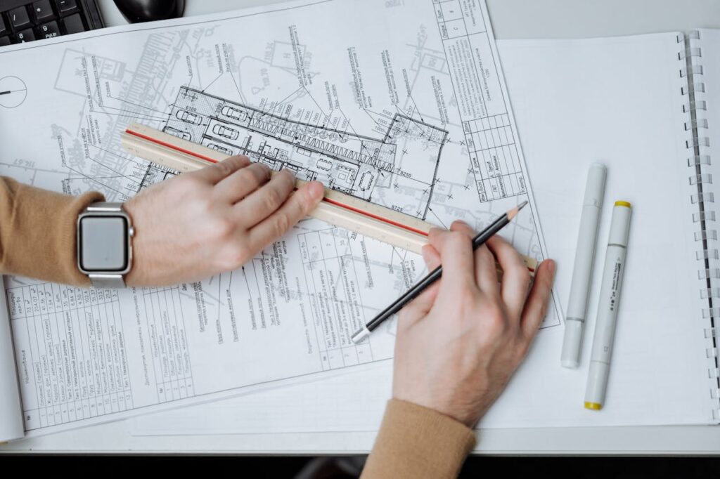 pexels-photo-5582597 An architect uses a ruler and pencil on blueprints, showcasing workspace and planning.